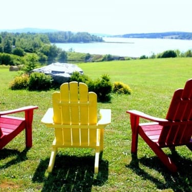 Three adirondack chairs overlooking the ocean