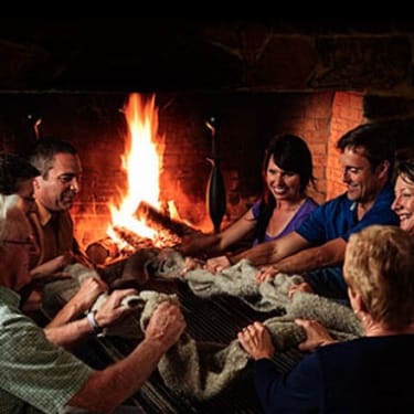 A group of people sit in front of a large fire